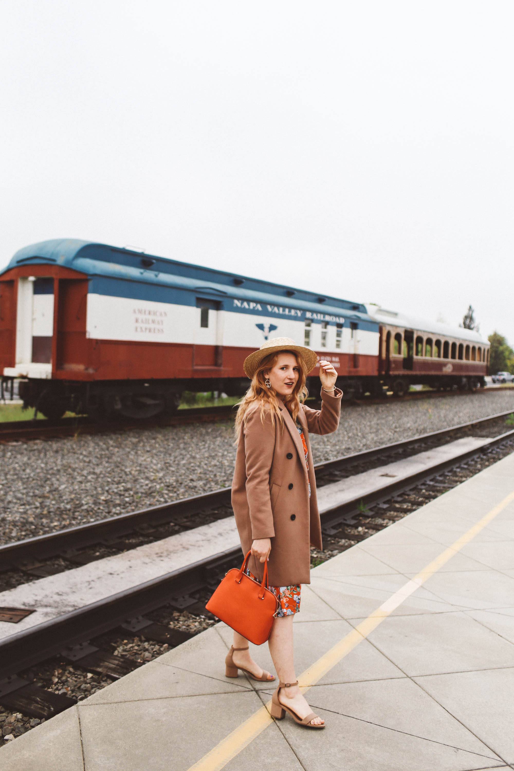 Woman in a tan coat and straw hat on the platform at Napa Vallley Wine Train