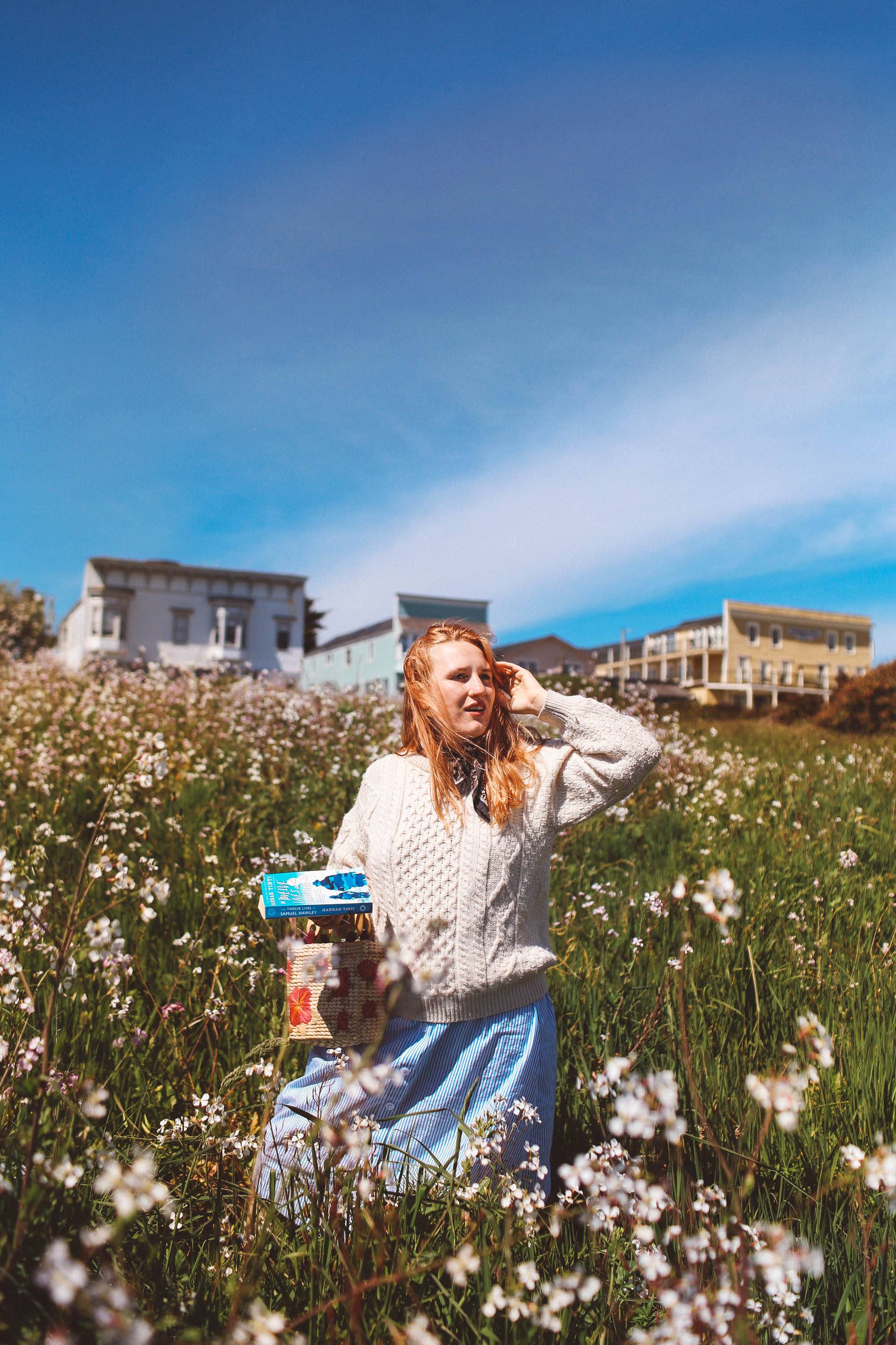 Woman in white wool sweater standing in flowers