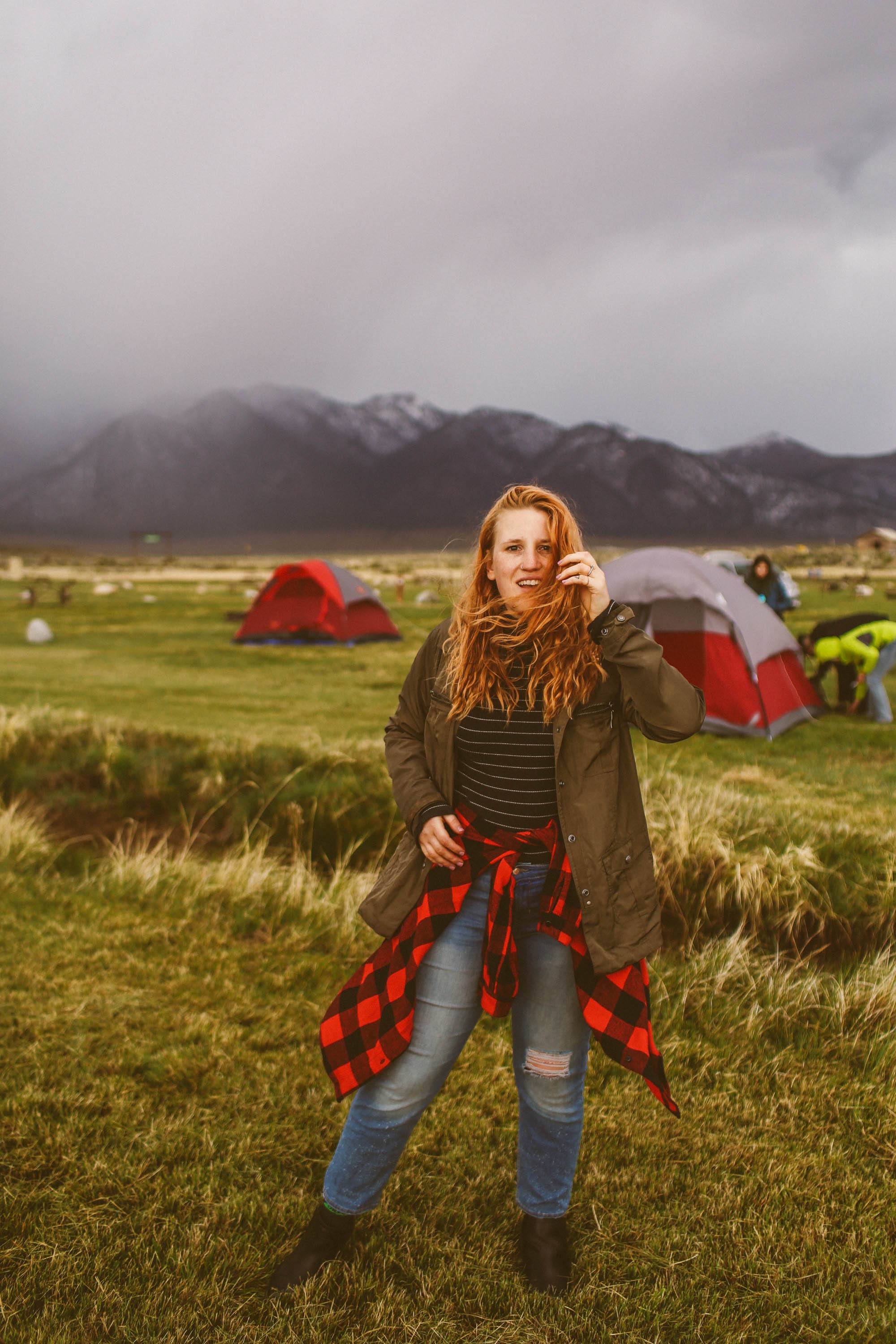 woman standing in the grass at a campground in the mountains