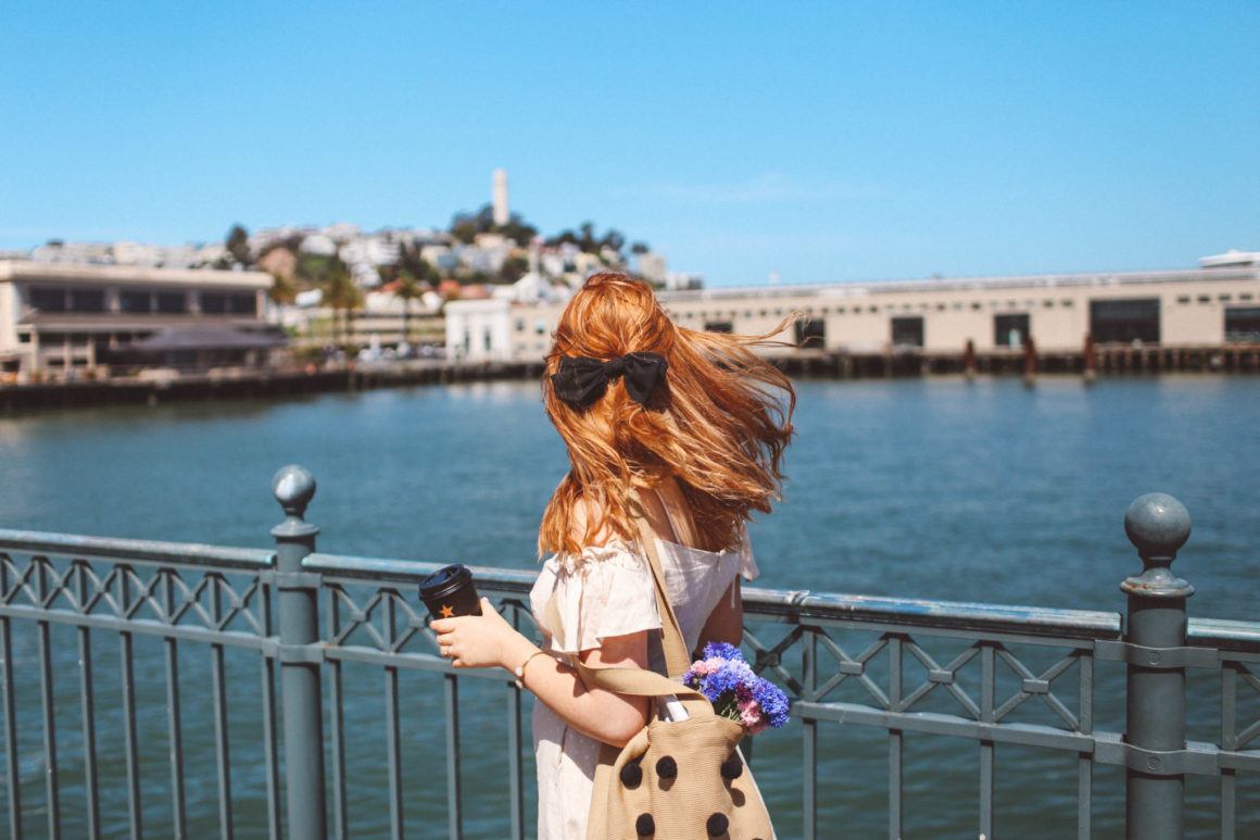 Woman holding coffee looking out over the water