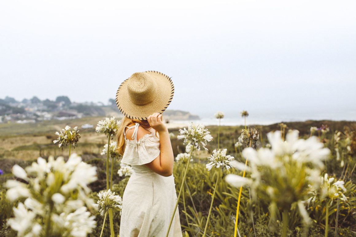 Woman in a dress and straw hat among the flowers