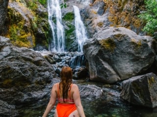 Kara of Whimsy Soul hikes to Feary Falls in Mount Shasta, a stunning small waterfall in Northern California. She is wearing an orange swimsuit