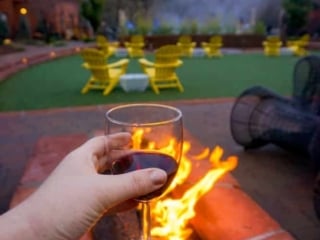 Kara of Whimsy Soul enjoys a glass of wine in Sedona Arizona in her Airbnb next to a fire and Red Rocks
