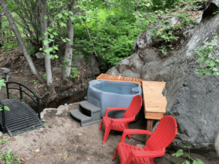 Leavenworth airbnb cabin with hot tub by the creek and red lawn chairs to sit outside