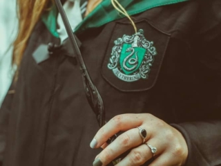 Kara holding her wand donning her Slytherin robes