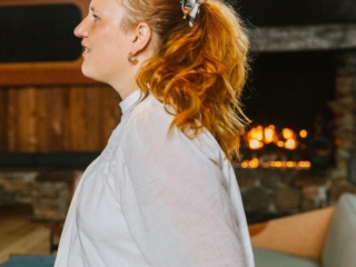 California travel blogger Kara Harms sits in the lobby of Timber Cove Resort wearing a white shirt and jeans