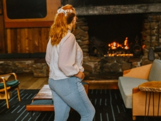 California travel blogger Kara Harms sits in the lobby of Timber Cove Resort wearing a white shirt and jeans